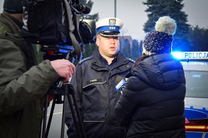 Policjant stoi przed kamerą i udziela wywiadu.