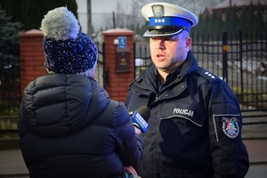 Policjant stoi przed kamerą i udziela wywiadu.