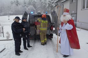 policjanci, strażak i Święty Mikołaj stoją przed radiowozem