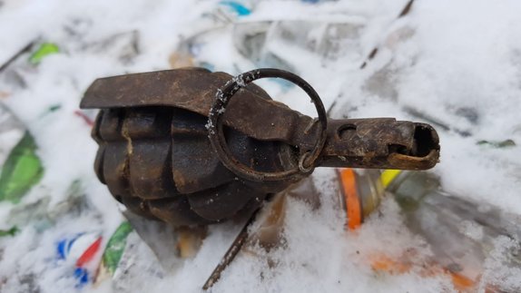 Zdjęcie kolorowe wykonane w porze dziennej , przedstawia granat ręczny F1 z zawleczką i zapalnikiem znaleziony na wysypisku odpadów w Przemyślu.