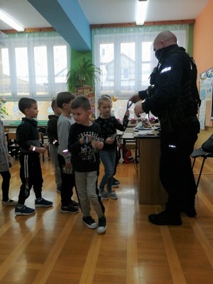 Policjant rozdaje dzieciom odblaski