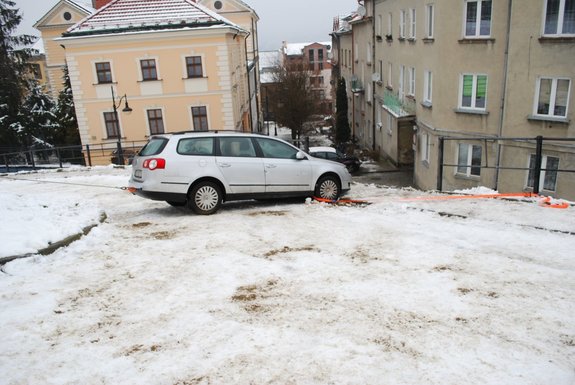 Zdjęcie przedstawia miejsce zdarzenia drogowego w Przemyślu na ul. Karmelickiej. Na zdjęciu widoczny pojazd m-ki VW Passat koloru białego stojący nas skarpą.