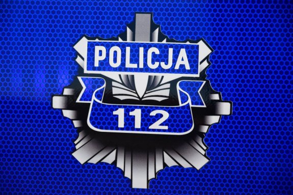 grafika z policyjną odznaką na niebieskim tle. Widoczny napis Policja, poniżej numer 112
