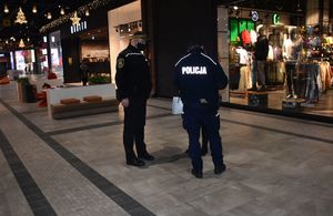 Policjant i strażnik miejski legitymują osobę w galerii handlowej