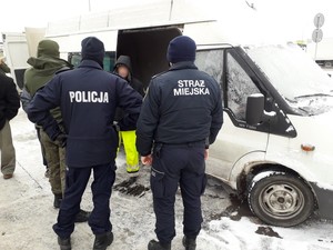 Funkcjonariusz Policji, Straży Miejskiej oraz Straży Rybackiej podczas kontroli miejsca handlu żywymi rybami w Krośnie