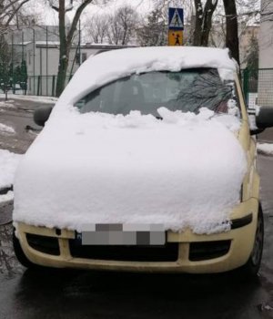 Zdjęcie przedstawia zaśnieżony samochód koloru żółtego