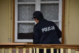 Policjantka zagląda przez okno do wnętrza domu