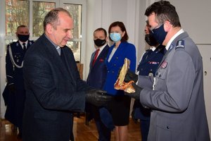 Kapelan Podkarpackiej Policji ks. Marek Buchman przy mikrofonie wręcza pamiątkową figurę inspektorowi Zbigniewowi Sowie (po prawej)