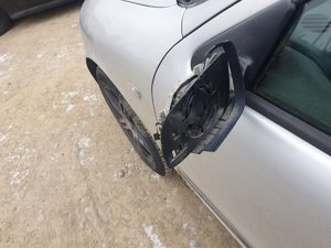 Zdjęcie przedstawia uszkodzone zewnętrzne lusterko samochodu osobowego