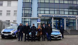 Zdjęcie grupowe Komendanta Powiatowego Policji w Jarosławiu z lokalnymi samorządowcami. W tle nowe radiowozy
