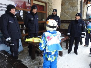 policjanci podczas prelekcji dla dzieci na stoku, na pierwszym planie dziecko w kasku narciarskim