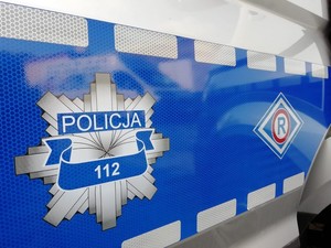 logotyp policyjnej odznaki oraz Wydziału Ruchu Drogowego na niebiesko - szarym tle drzwi policyjnego radiowozu