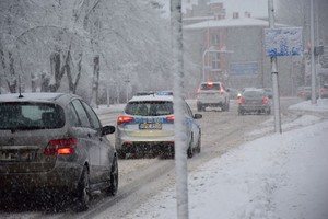 policyjny radiowóz na zaśnieżonej miejskiej drodze poruszający się w ciągu innych pojazdów