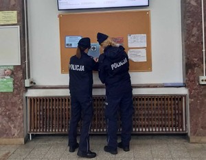 Dwie umundurowane policjantki umieszczają informację na tablicy schroniska.