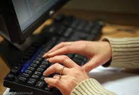 Zdjęcie kolorowe przedstawia klawiaturę komputera w kolorze czarnym a nad klawiatura widoczne są ręce  kobiety.