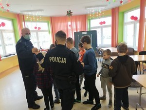 policjanci rozdają odblaski dzieciom podczas spotkania w świetlicy