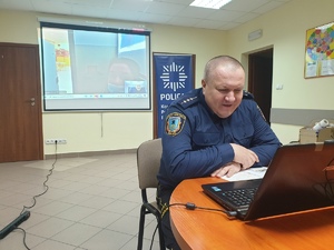 strażnik miejski podczas swojego wykładu, mężczyzna siedzi przed komputerem i uśmiecha się do dzieci