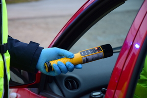 Policjant kontroluje stan trzeźwości kierowcy, przy użyciu urządzenia AlcoBlow