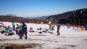 policjantka na tle uczestników zimowiska narciarskiego na stoku w Chyrowej