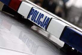 Zdjęcie kolorowe przedstawia belkę w samochodzie policyjnym ze światłami w kolorze czerwonym i niebieskim na środku belki widnieje napis POLICJA w białym kolorze