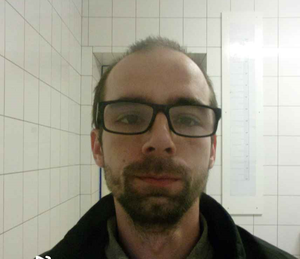 Na zdjeciu poszukiwany Konrad Witkowski, wiek z wyglądu ok. 30-35 lat, włosy krótkie ciemne, na twarzy okulary w czarnych oprawkach oraz krótki zarost - bródka i wąsy.