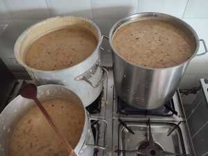 Grochówka w kotłach na kuchni gazowej. Trzy metalowe kotły wypełnione grochówką.