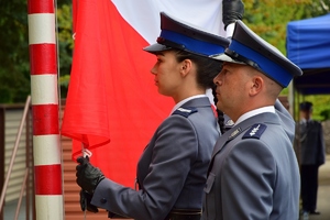 policjantka wraz z policjantem wciągają na maszt flagę