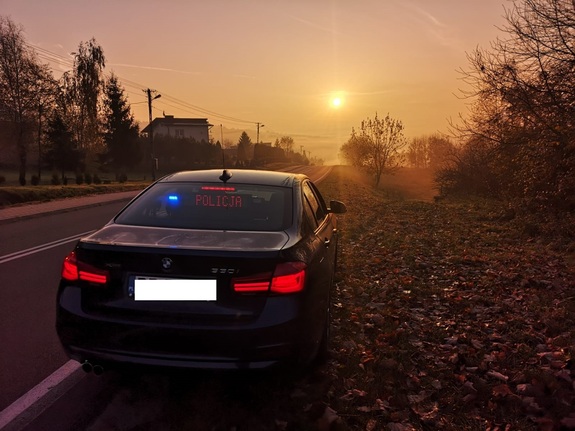 Zdjęcie kolorowe wykonane w porze nocnej przedstawia radiowóz nieoznakowany policyjny z włączonymi światłami błyskowymi. Pojazd marki –BMW jest w kolorze czarnym