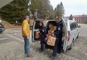 Na zdjęciu przed ośrodkiem w Polańczyki policjanci wypakowują przywiezione dary.