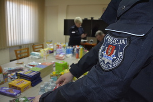 Zdjęcie kolorowe wykonane w porze dziennej -przedstawia pokój Komendy Miejskiej Policji w Przemyślu w którym są  składowane dary dla uchodźców z Ukrainy.