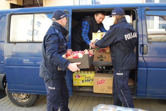 Na zdjęciach na dziedzińcu rzeszowskiej komendy umundurowania policjanci pakują do furgonetki zakupione ze składek artykuły pierwszej potrzeby dla uchodźców z Ukrainy.