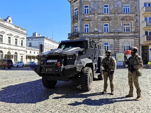 Zdjęcie kolorowe –przedstawia ul. Plac Legionów w Przemyślu. Na pierwszym planie widoczny pojazd policyjny „TUR” opancerzony a obok pojazdu stoi dwóch policjantów umundurowanych i uzbrojonych.