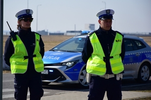 Dwoje policjantów ruchu drogowego. W tle radiowóz.