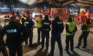 Zdjęcie kolorowe wykonane w porze nocnej -przedstawia dworzec PKP  w Przemyślu na peronie widoczny pociąg oraz policjanci niesilący pomoc uchodźcom