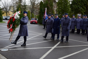 Komendant Wojewódzki Policji w Rzeszowie wraz z zastępcami składają wieniec pod tablicą pamiątkową. Po lewej na pierwszym planie policjant z wieńcem.