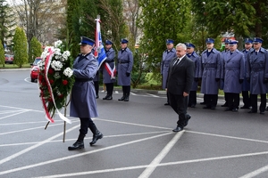 Wicemarszałek Województwa Podkarpackiego składa wieniec pod tablicą. Po lewej na pierwszym planie policjant z wieńcem.