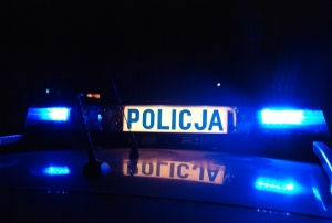 Zdjęcie przedstawia dach radiowozu wraz z sygnalizacją świetlną w kolorze niebieskim oraz napisem policja.