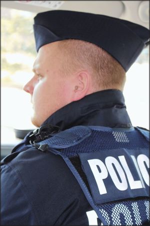 Na zdjęciu umundurowany policjant. Zdjęcie zrobione z bocznego profilu