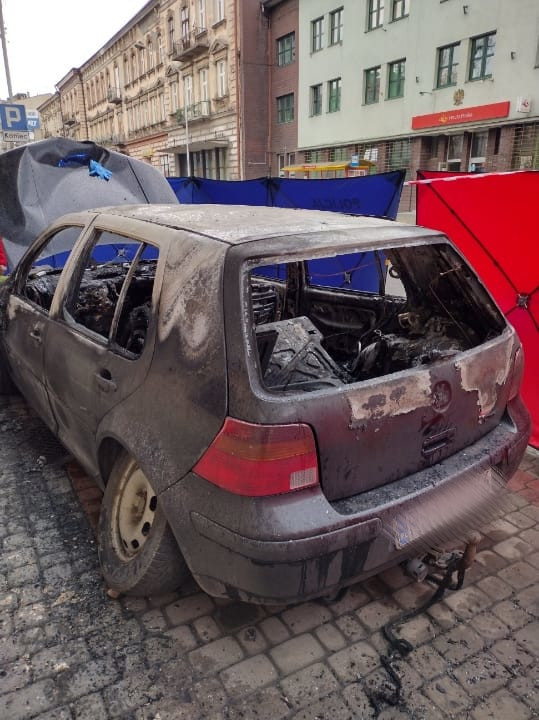 Zdjęcie kolorowe wykonane w porze dziennej przedstawia spalony wrak samochodu marki volkswagen.