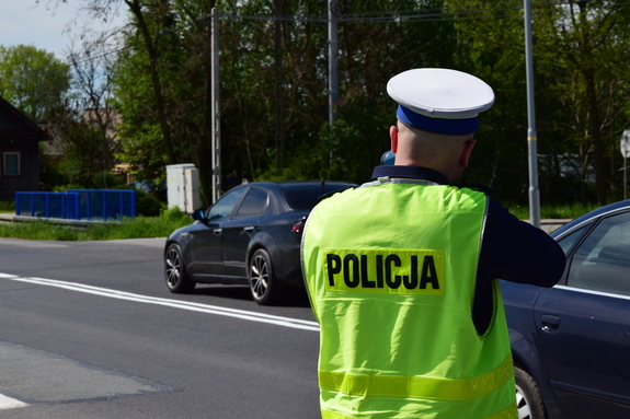 policjant ruchu drogowego w żółtej kamizelce wykonuje na drodze pomiar prędkości
