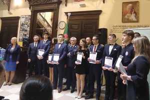 Komendant Wojewódzki Policji w Rzeszowie podczas zakończenia roku szkolnego klas mundurowych. Komendant (stoi w środku) wśród uczniów, którzy trzymają w rękach dyplomy.