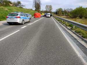 Zdjęcia z miejsca wypadku - prosty odcinek drogi, radiowóz, czerwony parawan, przewrócony motocykl i inne pojazdy