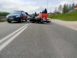 Zdjęcia z miejsca wypadku - prosty odcinek drogi, radiowóz, czerwony parawan, przewrócony motocykl i inne pojazdy