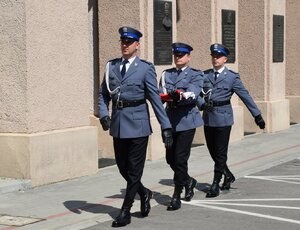 policjanci maszerujący do masztu z flagą