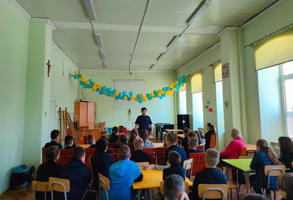 Sala w której znajdują się uczniowie. W tle policjantka w czasie prelekcji.