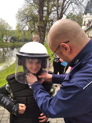 Policjant pomaga chłopcu założyć kask policyjny.
