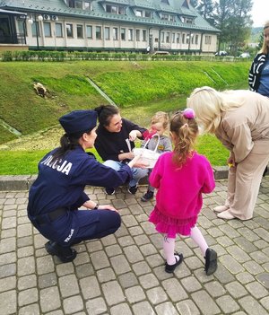 Policjantka rozdaje dzieciom upominki.
