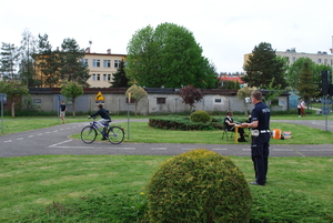 Policjant ruchu drogowego nadzorujący przejazd rowerem ucznia uczestniczącego w turnieju