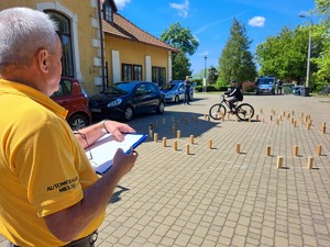 tor sprawnościowy, na fotografii rowerzysta przejeżdzający przez tor na rowerze pod okiem prowadzącego konkurencję