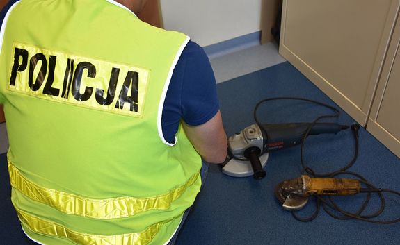 Dwie szlifierki odzyskane przez policjantów. Przy elektronarzędziach widoczny jest mężczyzna ubrany w kamizelkę z napisem na plecach Policja.